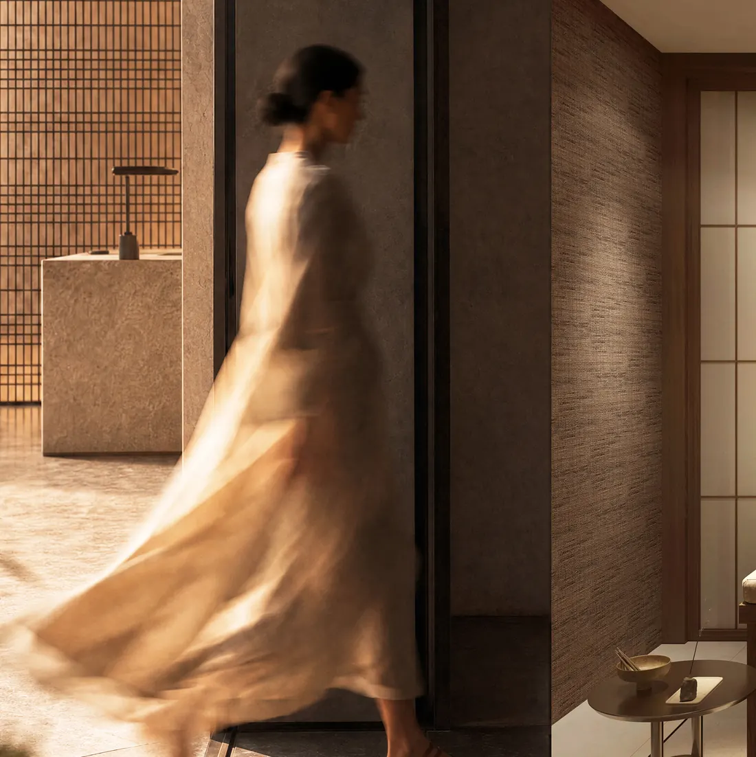 A woman walks through a softly lit lobby of stone and timber